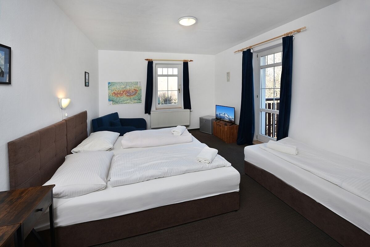 Ein Hotelzimmer mit einem großen Bett, einem Schreibtisch, einem Fernseher und einem Fenster mit Vorhängen.