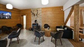 A wooden interior with a stone fireplace, a mounted deer skull, and a television on the wall. - Penzión Chata Valaška (Vysoke Tatry)