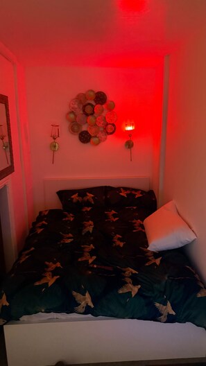A bedroom with a bed, a wall-mounted light, and a decorative wall piece. - A Double Room in a House Sleeps 2 With Parking (Croydon)