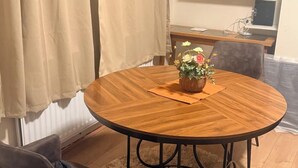 A round wooden dining table with a woven basket centerpiece, a single brown chair, and a fluffy rug. - House Sleeps 2 With Parking (Croydon)
