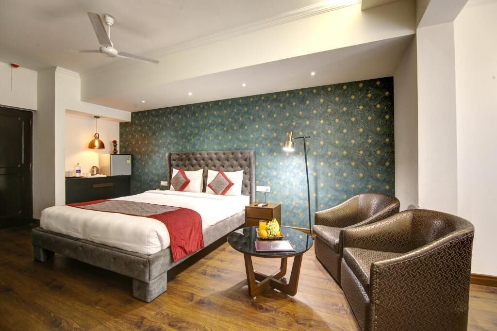 Un dormitorio con cama, mesita de noche, lámpara y dos sillas.