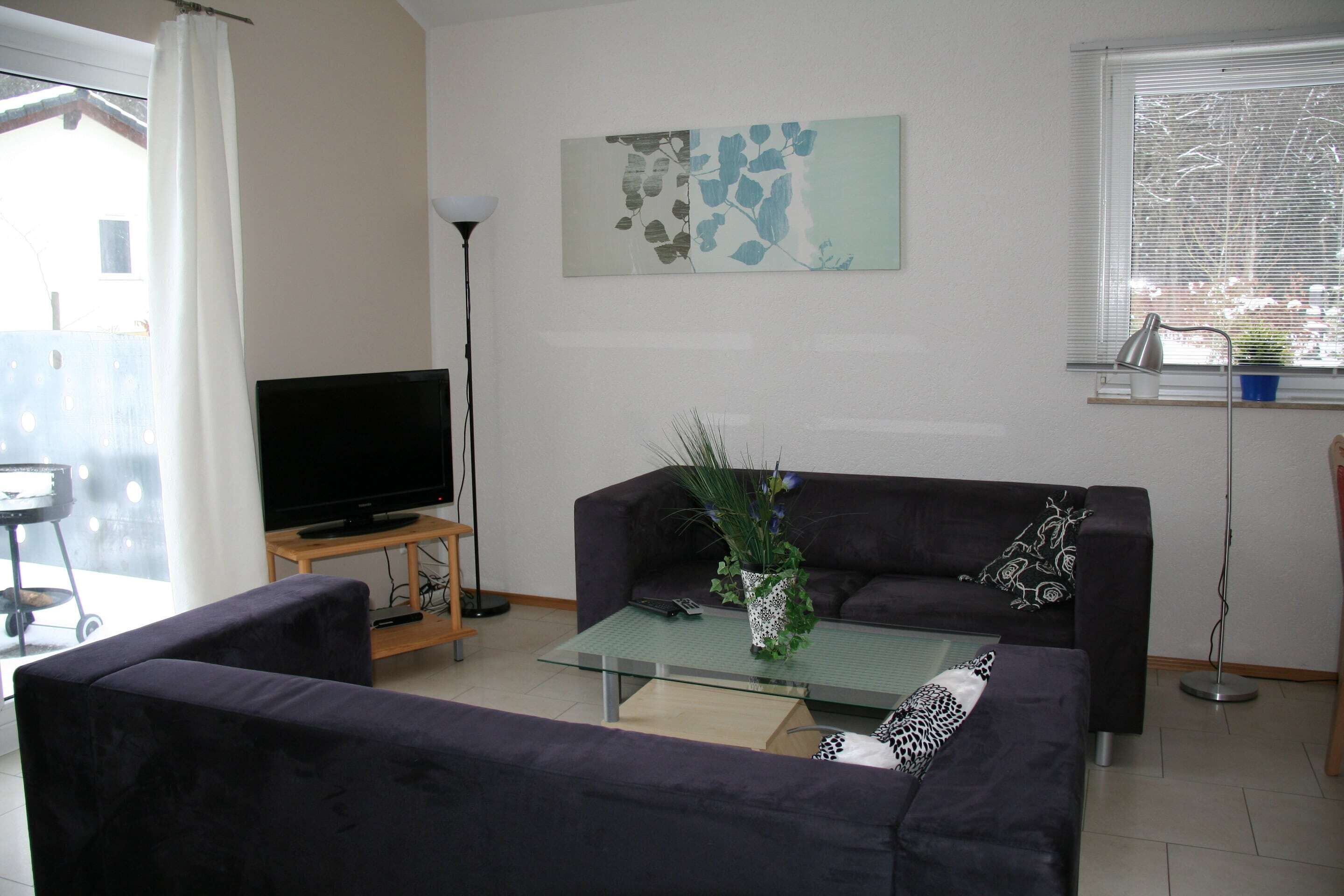 A living room with a sofa, a coffee table, a TV, and a painting on the wall.