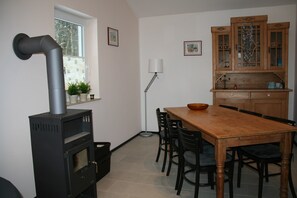 A kitchen with a stove, wooden cabinets, a dining table with chairs, and a window. - Bungalow Near Eifel Ski Lift (Gerolstein)