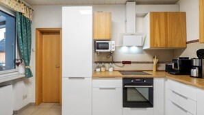 A compact kitchen with white cabinets, a microwave, a stove, and a coffee maker. - Holiday Home 'Family House with Huge Garden' with Sauna, Terrace and Wi-Fi (Jessen (Elster))