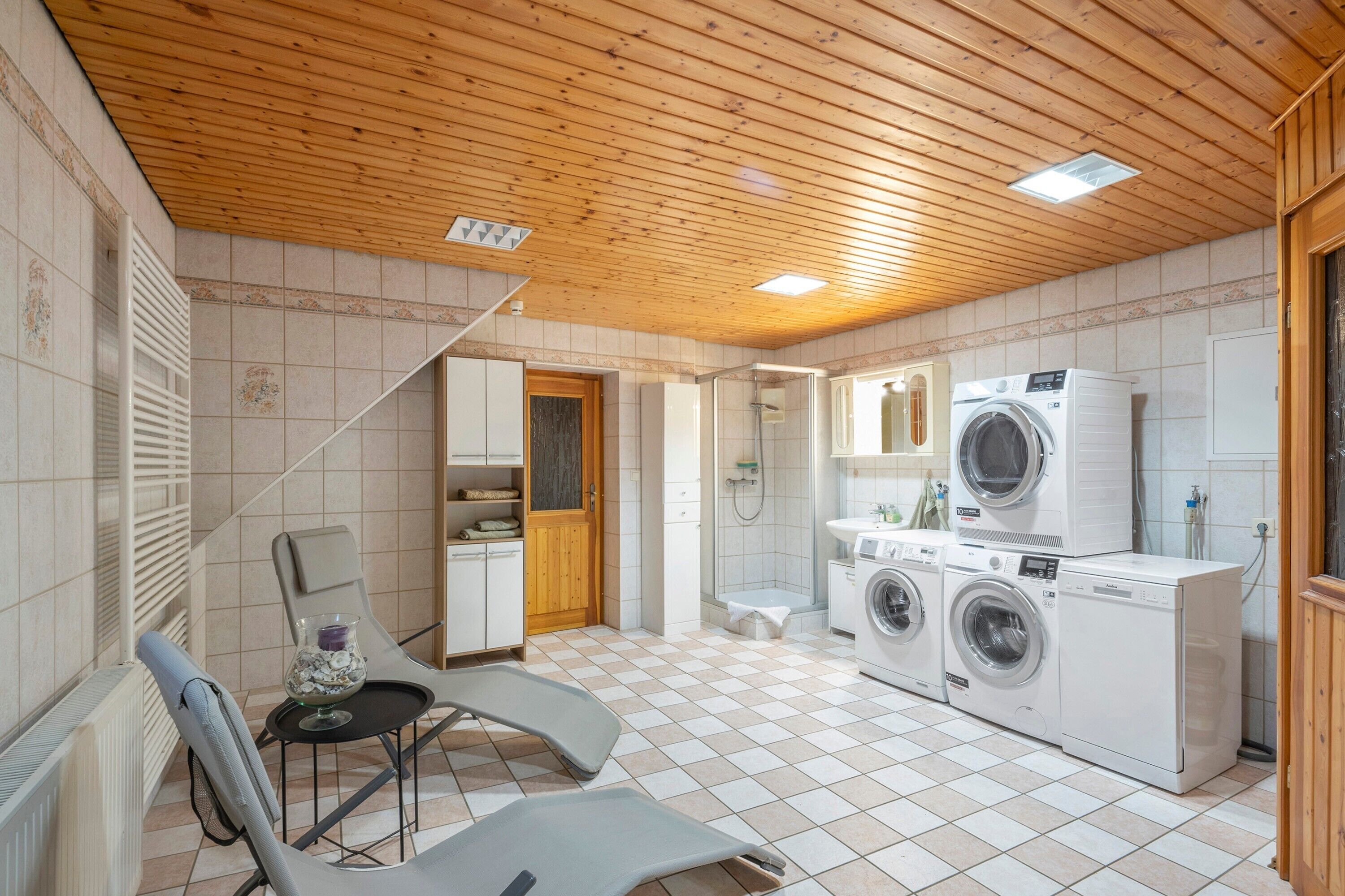 A compact kitchen with a washing machine, a sink, and a shower.
