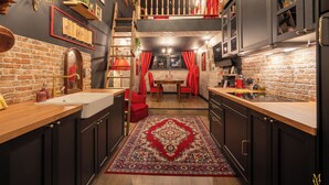Una cocina con pared de ladrillo, encimeras de madera y alfombra roja.