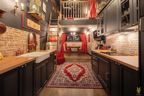 A kitchen with a brick wall, wooden countertops, and a red rug. - Maison Wingardium - Private Cinema & View of the Cité de Carcassonne and the Pyrenees (Carcassonne)