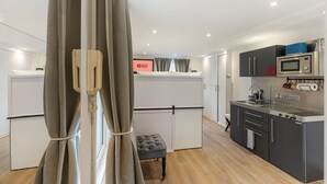 Une cuisine compacte équipée d’un four à micro-ondes, d’une cuisinière et d’un évier. Un petit coin salon avec un banc rembourré est également disponible.