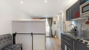 Une cuisine compacte équipée d’un réfrigérateur, d’un coin repas avec une banquette et d’un four à micro-ondes.