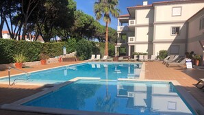 Ein rechteckiger Pool mit Metallleiter, umgeben von einer gefliesten Terrasse.