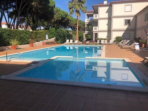 Ein rechteckiger Pool mit Metallleiter, umgeben von einer gefliesten Terrasse.