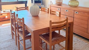 Uma sala de jantar com mesa e cadeiras de madeira, televisão e obras de arte nas paredes.