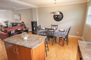 A kitchen with a granite countertop, a dining table with checkered tablecloths, and a microwave on the wall.