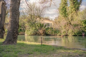 A riverside property with a large water wheel, a house with a tiled roof, and lush greenery. - Villa Alba, house with private access to the river, swimming and canoes (L'Isle-sur-la-Sorgue)