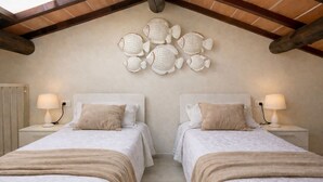 A bedroom with two beds, a ceiling with exposed wooden beams, and a wall-mounted decorative fish sculpture. - Il Cavaliere - Fantastic sea view, pool, beach only 5 minutes on foot (Lacona)