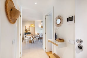 A modern interior with a dining area, a wall-mounted TV, and a door with a keypad lock. - Casas do Forte CB in Cabanas de Tavira (Tavira)