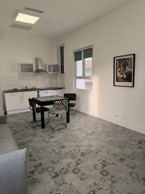 A modern kitchen with white cabinets, a dining table with chairs, and a patterned floor. - Art Deco apartment, swimming pool, private terrace, parking, city center (Béziers)