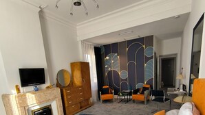 Une chambre d’hôtel dotée d’un grand lit, d’une télévision, d’une cheminée, d’un bureau et d’un décor mural moderne.