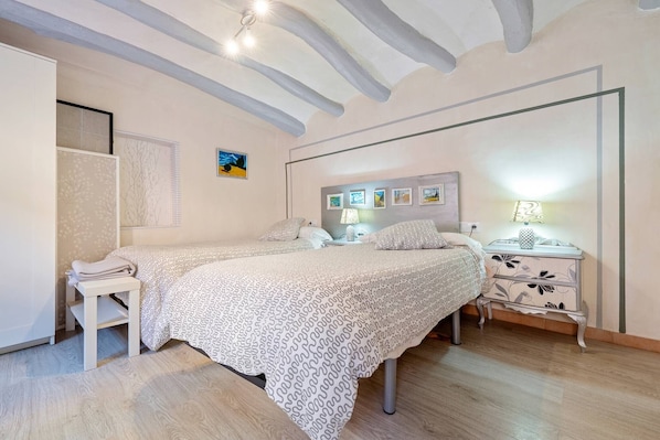 Un dormitorio con dos camas, una mesita de noche, una lámpara y un estante en la pared.