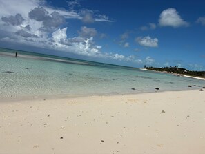 Una playa con agua turquesa cristalina, arena blanca y rocas dispersas.