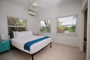 A bedroom with a bed, a nightstand, a ceiling fan, and windows with blinds. - Cozy home/Pool/Volleyball court/ near the beach (Providenciales)
