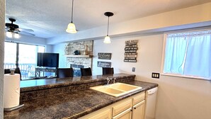 A kitchen with a granite countertop, white cabinetry, a sink, and pendant lighting. - Stunning Lake Views at Indian Pointe! (Osage Beach)