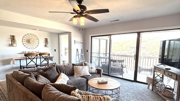 A living room with a sofa, coffee table, and a ceiling fan. - Stunning Lake Views at Indian Pointe! (Osage Beach)