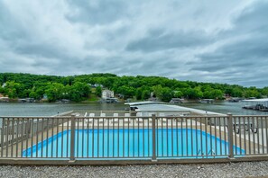Ein Schwimmbad mit Holzterrasse und Blick auf einen Fluss und bewaldetes Gebiet.