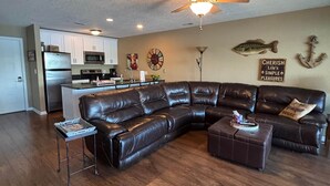A living room with a leather sectional sofa, a coffee table, a small side table, and a ceiling fan. - Beautiful Views at Bay Point Condominiums! (Osage Township)