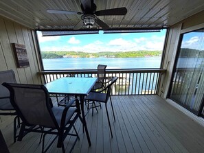 Eine überdachte Terrasse mit Tisch und Stühlen, einem Deckenventilator und Blick auf einen See.