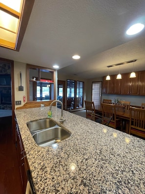 A kitchen with granite countertops, a stainless steel sink, wooden cabinets, and pendant lighting. - Lake of the Ozarks Hotspot! Main Channel Views! (Adair Township)