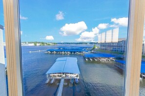 A marina with docked boats, a large covered boat launch ramp, and a building with multiple floors in the background. - HUGE Views at Bridgepointe Condos! (Osage Beach)
