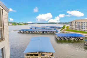 A marina with docked boats, a building with a blue roof, and a distant view of a large hotel. - HUGE Views at Bridgepointe Condos! (Osage Beach)