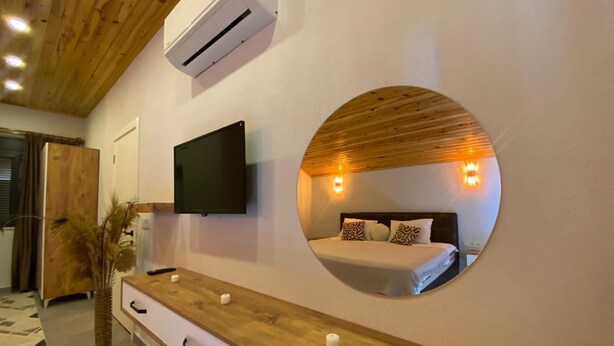 A bedroom with a bed, a TV, a round mirror, and a wooden dresser. - Kent Villas Heated Pool Villas (Demre)