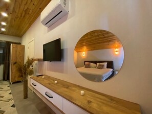 A bedroom with a bed, a TV, a round mirror, and a wooden dresser. - Kent Villas Heated Pool Villas (Demre)