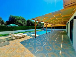 Una piscina al aire libre, sombrillas, sillones reclinables de piscina