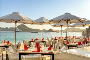 A seaside restaurant with tables set for dining, large umbrellas, and a view of the sea and ships. - Villa del Palmar Beach Resort Cabo, San Lucas (Cabo San Lucas)