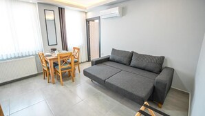 Ένα σύγχρονο σαλόνι με έναν καναπέ, ένα τραπέζι φαγητού, καρέκλες και ένα καλοριφέρ.
