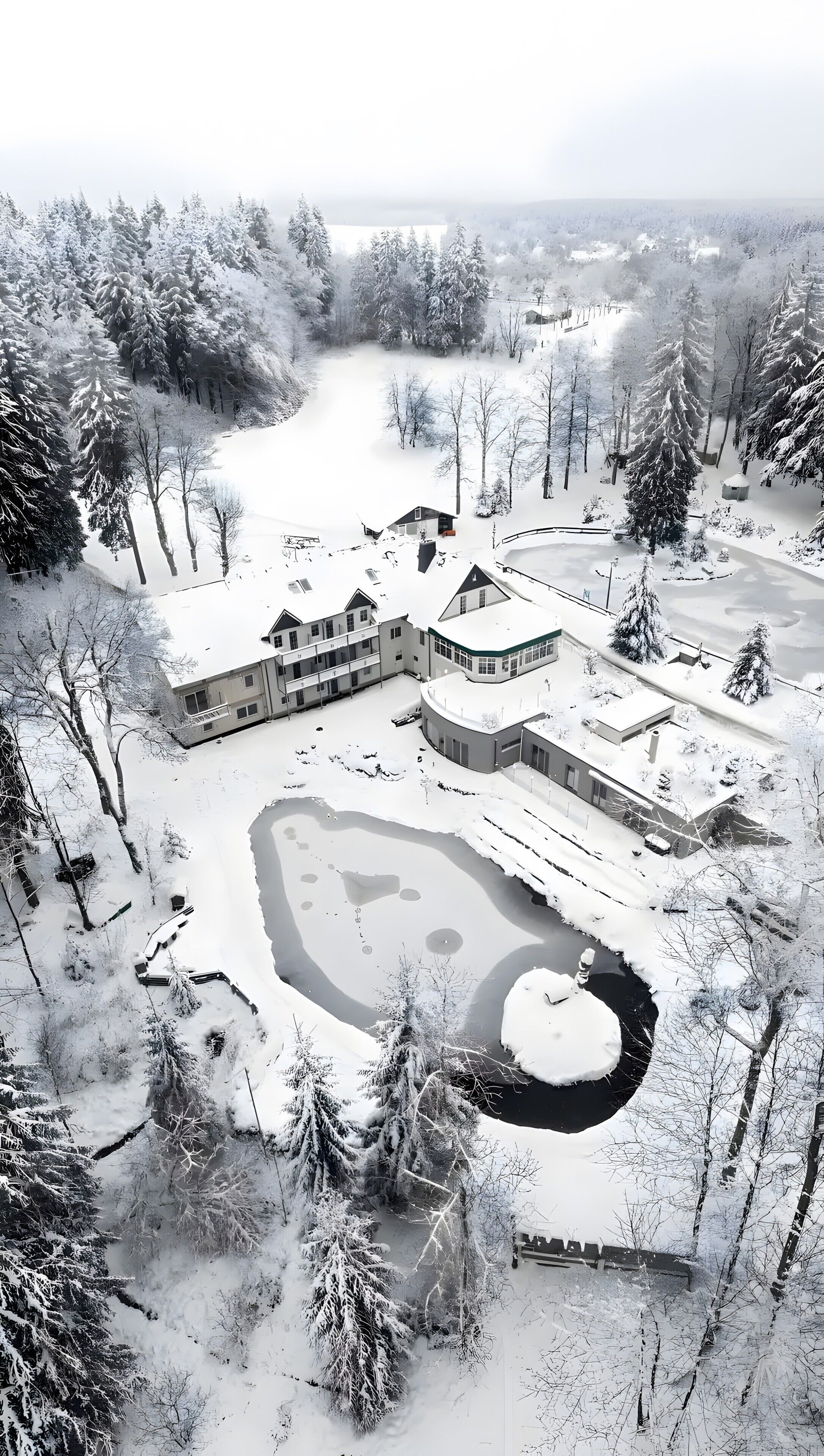 A snow-covered landscape with a large building complex, including multiple structures and a central courtyard.