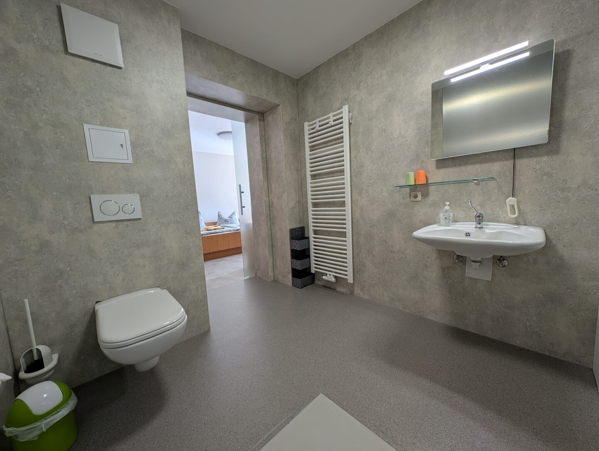 Et badeværelse med toilet, håndvask og bruseområde.