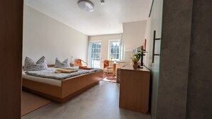 A bedroom with a bed, a desk, a chair, and a window. - Apartment in A Hotel 'Pensionszimmer 24 Qm Mit Balkon (copy)' with Shared Garden, Balcony and Wi-Fi (Suhl)