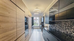Una cocina moderna con detalles de madera y piedra, una isla central e iluminación colgante.
