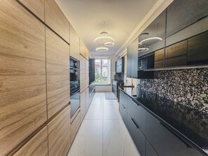 A modern kitchen with wood and stone accents, a central island, and pendant lighting. - Luxury Apartment in Lucca (Lucca)