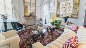 Una sala de estar con chimenea, un sillón verde, un sofá y una mesa de centro.