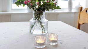 A table with a vase of flowers, two lit candles, and a hanging chandelier. - Central house with AC near the beach (Piteå)