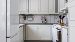 A kitchen with white cabinets, a wooden countertop, a hanging light fixture, and a tiled backsplash. - Central house with AC near the beach (Piteå)