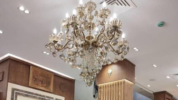 A lobby with a chandelier, an elevator, a staircase, and wooden paneling. - L amiral (Oran)
