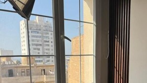 A room with a large window, a small table, and a view of buildings outside. - L amiral (Oran)