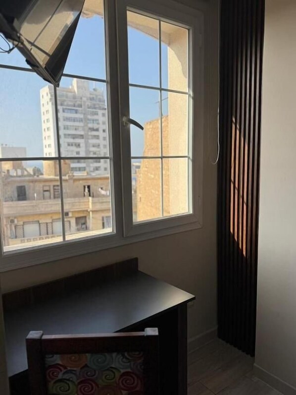 A room with a large window, a small table, and a view of buildings outside.