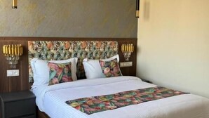 A neatly made bed with a floral-patterned headboard, a bedside table with a lamp, and a wooden floor. - L amiral (Oran)